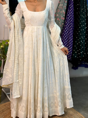 White lace dress with long sleeves and a matching shawl held by a person against a colorful background.