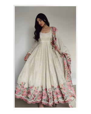 Woman wearing a white dress with floral embroidery and a matching dupatta.