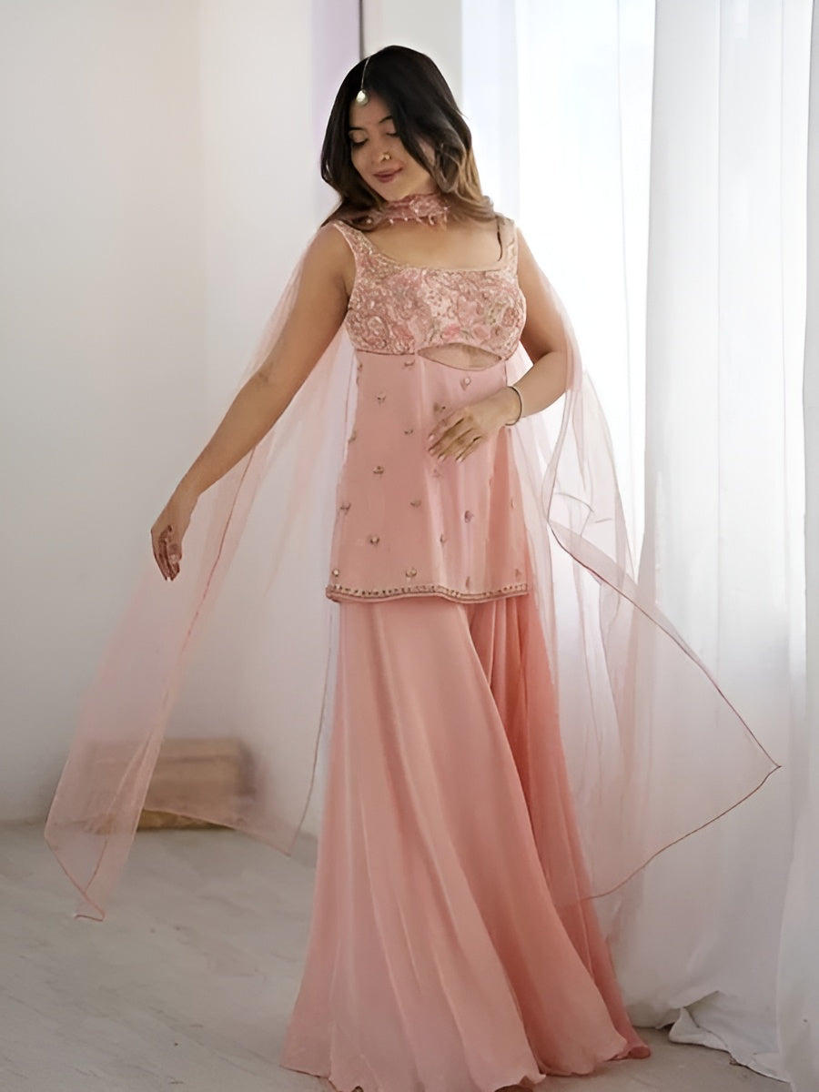 Woman wearing a pink traditional outfit with a sheer dupatta in a bright room.
