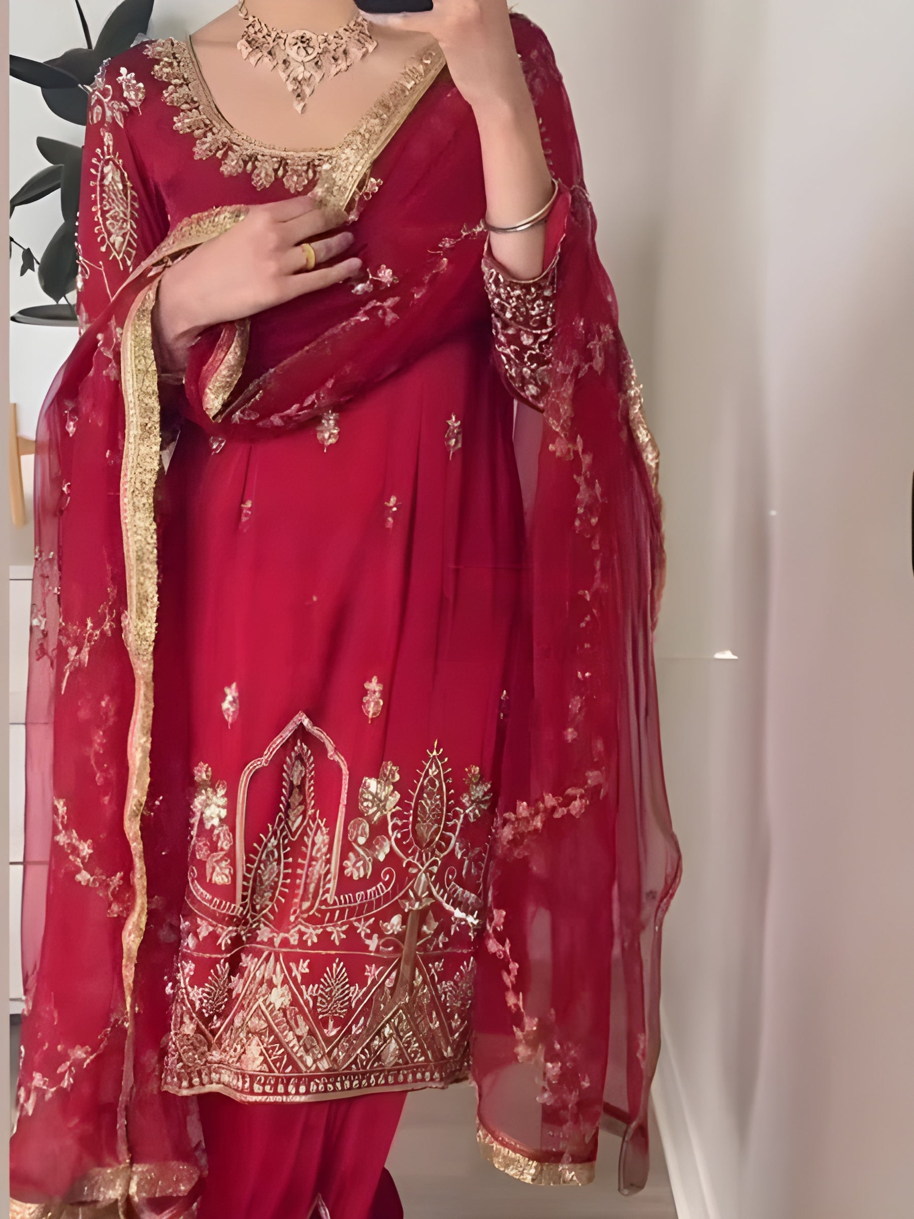 Red embroidered traditional outfit with gold details against a neutral background