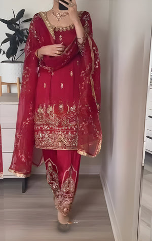 Red traditional outfit with gold embroidery in a room setting