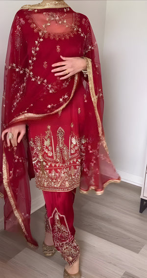 Red embroidered traditional outfit with a sheer dupatta on a plain background