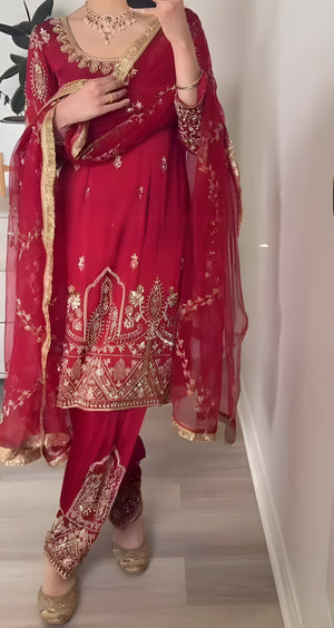 Red traditional outfit with gold embroidery and matching dupatta against a neutral background