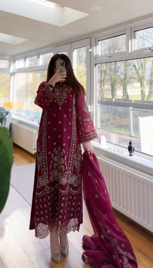 Person wearing a wine embroidered outfit in a room with large windows.