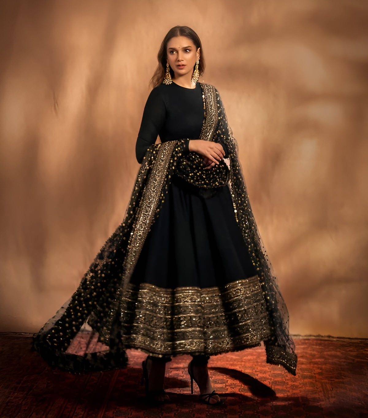 Woman wearing a black and gold traditional outfit with a textured background