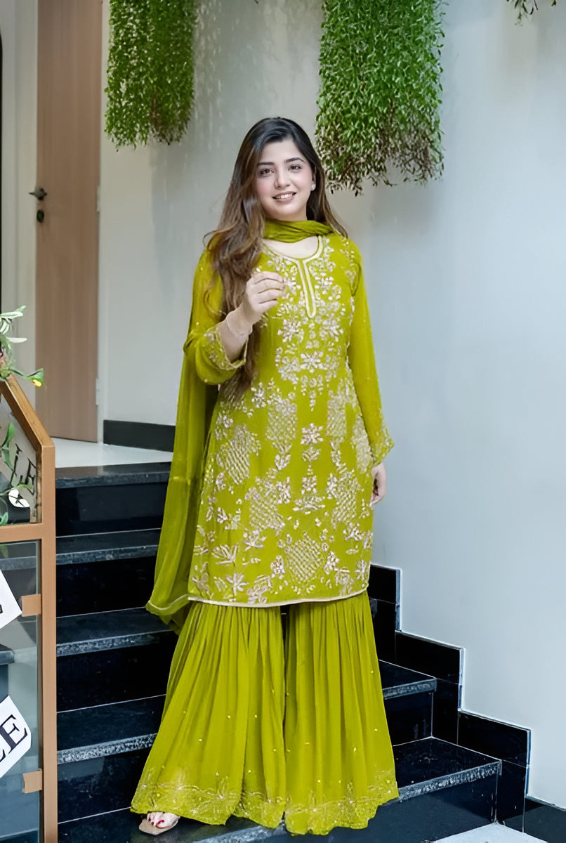 Woman in a green traditional outfit standing on a staircase with plants in the background