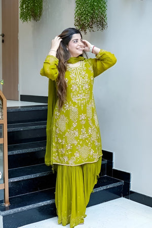 Woman in a green traditional outfit standing on a staircase.