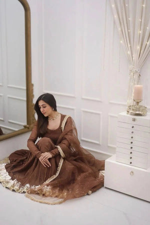Woman in a brown dress sitting on the floor in a room with white walls and decor.