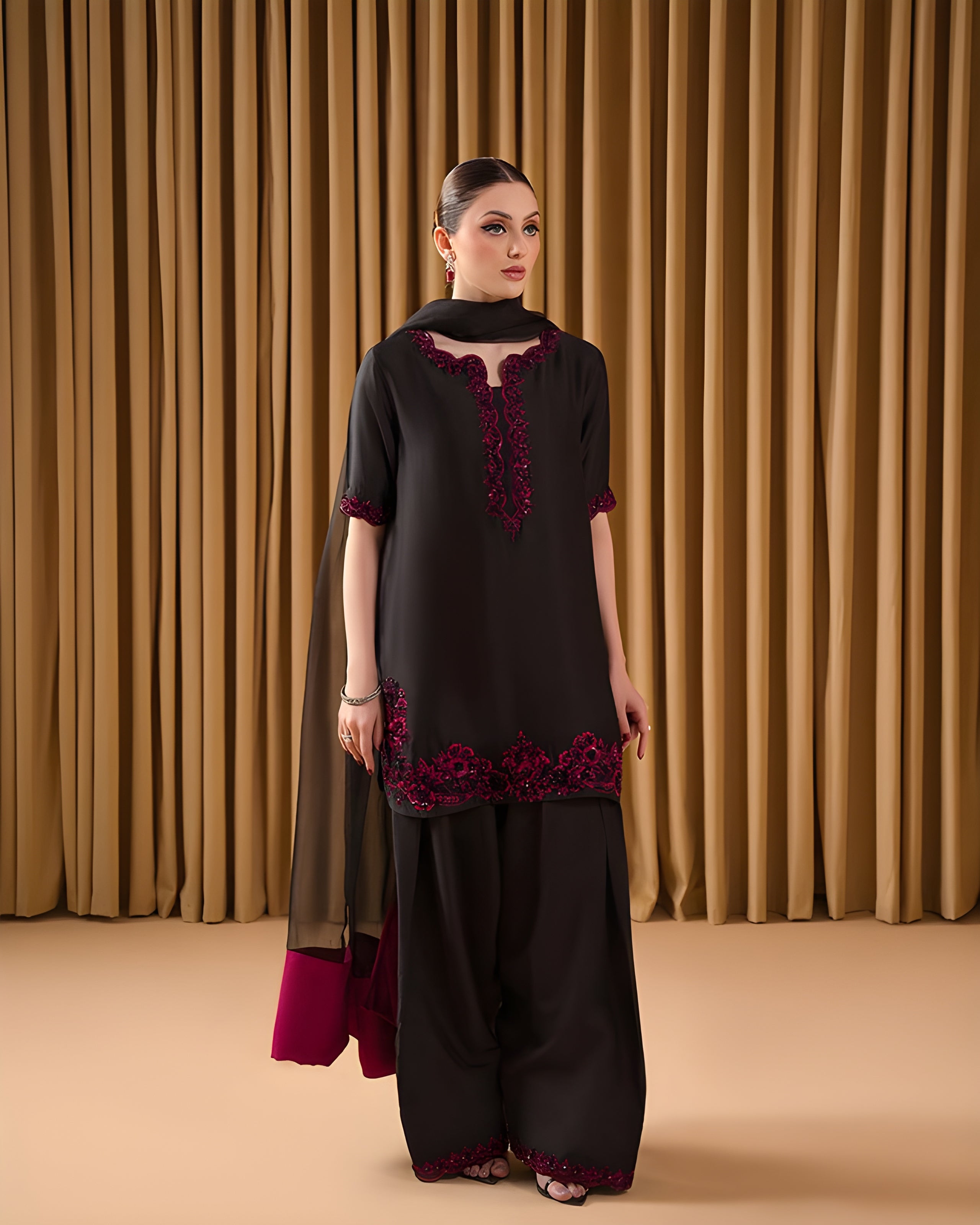 Woman wearing a black and red traditional outfit against a brown curtain background