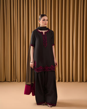 Woman wearing a black and red traditional outfit against a brown curtain background