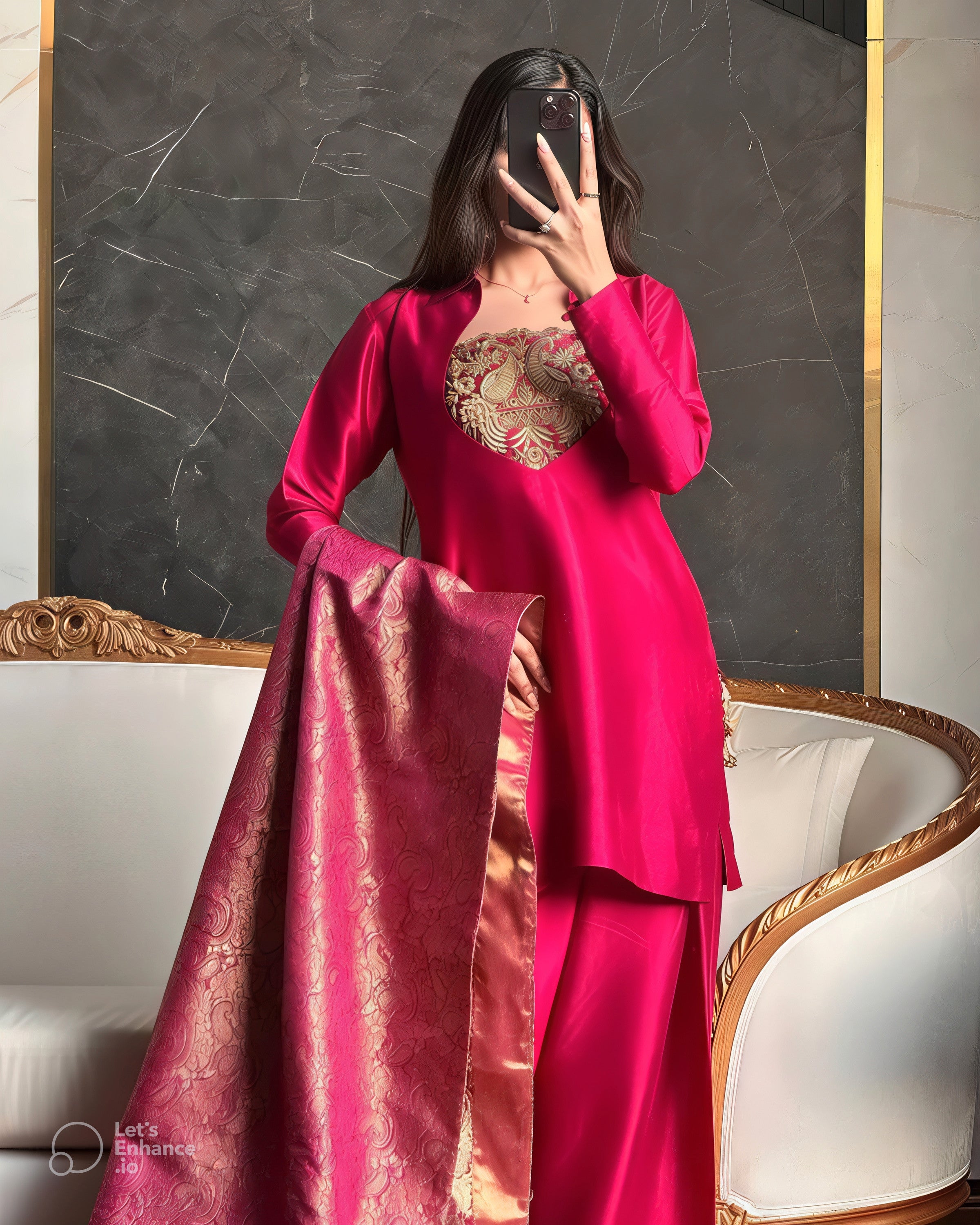 Person wearing a pink traditional outfit with gold embroidery in a decorative room.