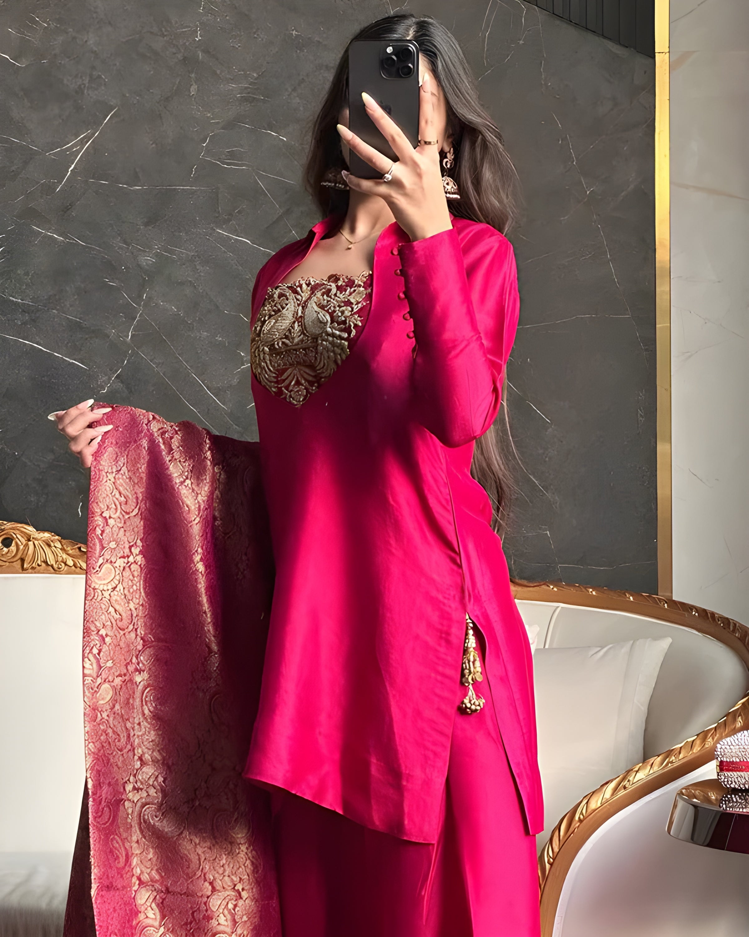 Person wearing a bright pink traditional outfit with gold embroidery, holding a matching dupatta.