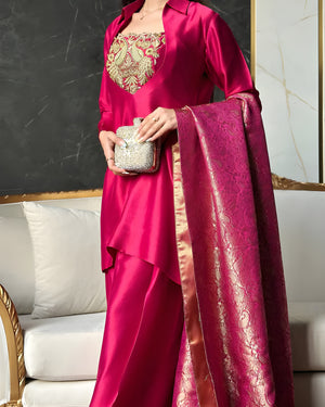 Person wearing a pink traditional outfit with gold embroidery, holding a matching dupatta.