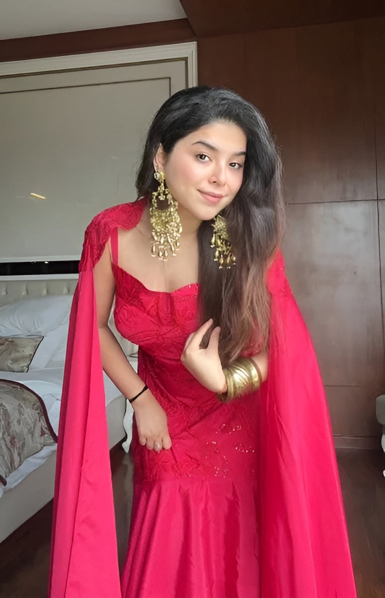 Woman in a red dress with gold jewelry indoors