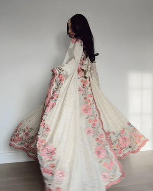 Woman holding a floral embroidered fabric against a white wall