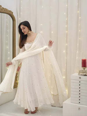 Woman in a white dress with a sheer dupatta in a decorated room with fairy lights.