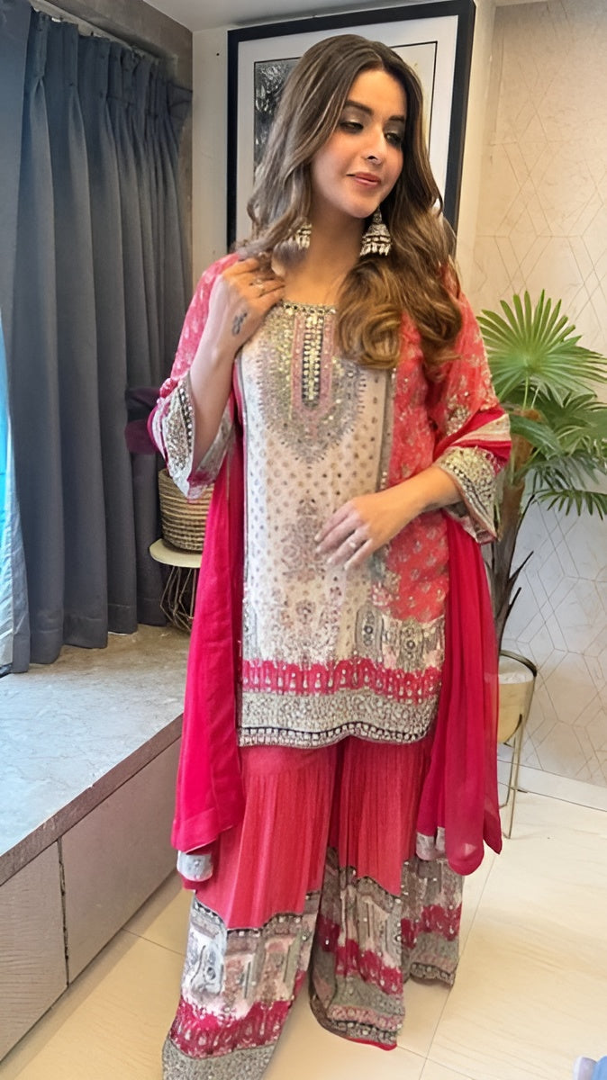 Woman wearing a traditional outfit with a pink dupatta in an indoor setting.