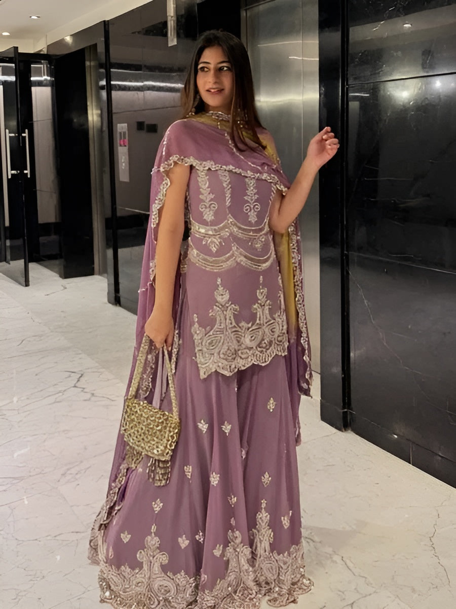 Woman in a purple embroidered outfit with gold details in an indoor setting