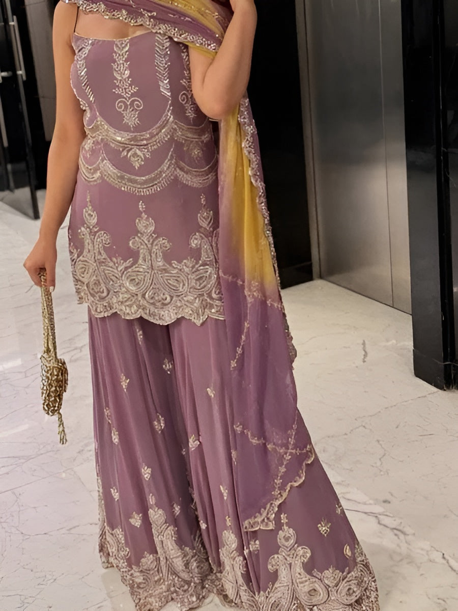 Person wearing a purple saree with gold embroidery in an indoor setting