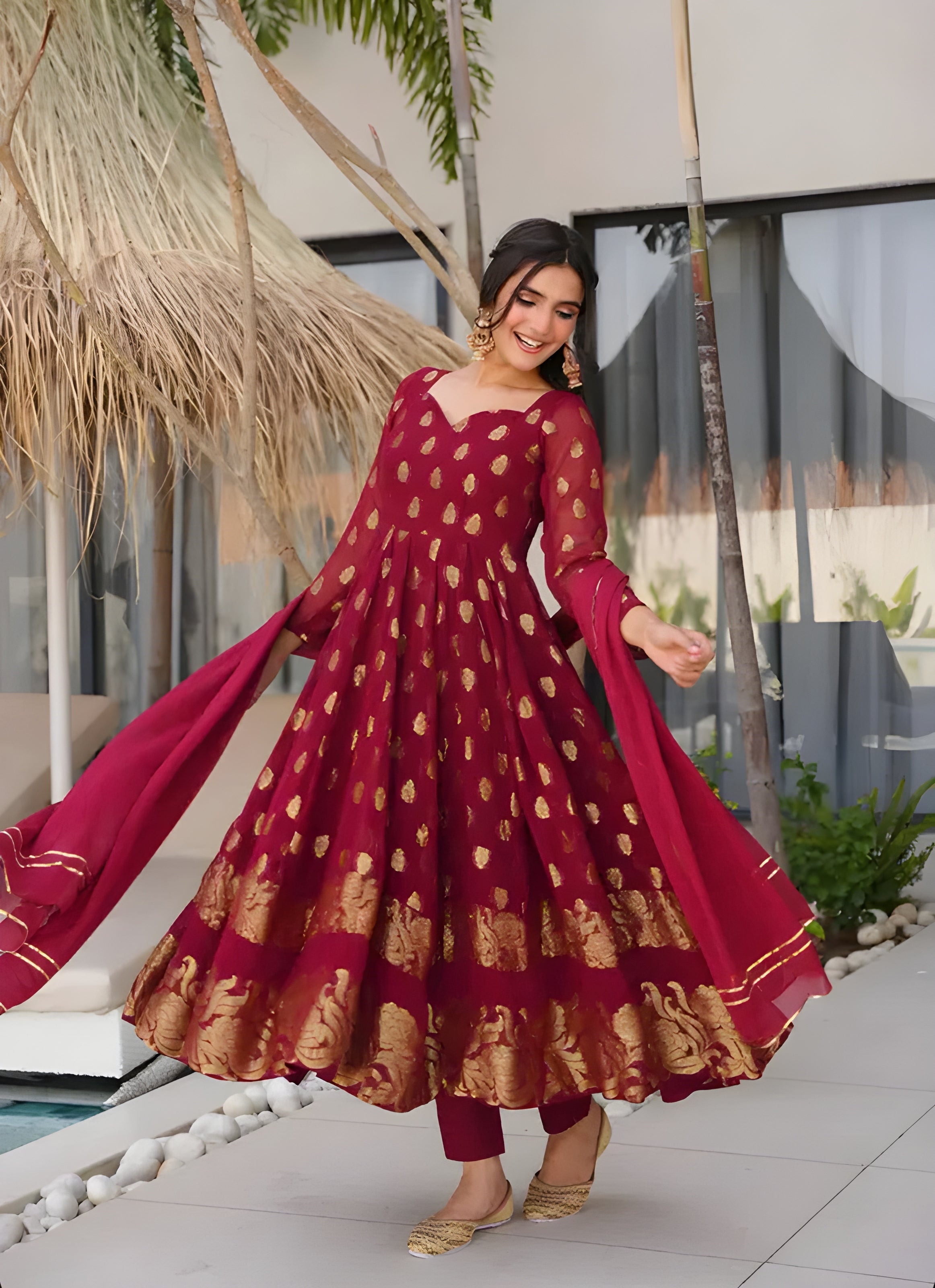 Woman in a red and gold traditional outfit standing outdoors.
