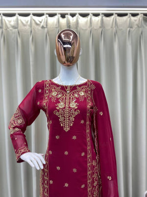 Wine embroidered dress on a mannequin with a metallic head against a white curtain background
